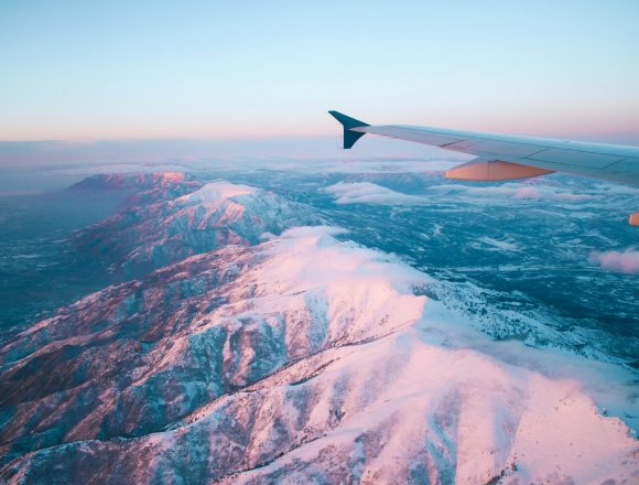 Photo by Elizabeth Camp plane flying above white mountains during daytime